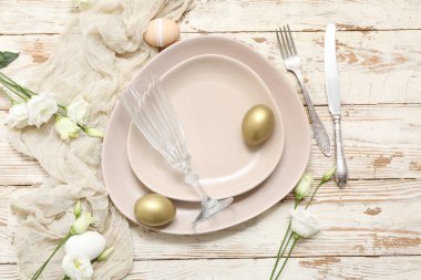 Paskalya yumurtaları ve beyaz ahşap arka planda Eustoma çiçekleri olan güzel bir masa.