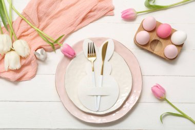 Paskalya yumurtaları ve beyaz ahşap arka planda lale çiçekleri olan güzel bir masa.