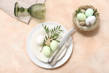 Paskalya yumurtaları ve bej arka planda ağaç dallarıyla güzel bir masa.