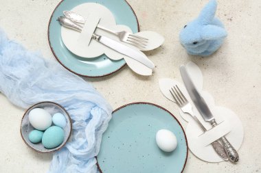 Paskalya yumurtaları ve beyaz arka planda mavi oyuncak tavşanla güzel bir masa.