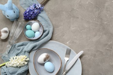 Paskalya yumurtaları, oyuncak tavşanlar ve gri arka planda güzel çiçekler.