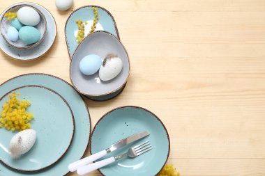 Paskalya yumurtaları ve ahşap arka planda mimoza çiçekleri olan güzel bir masa.