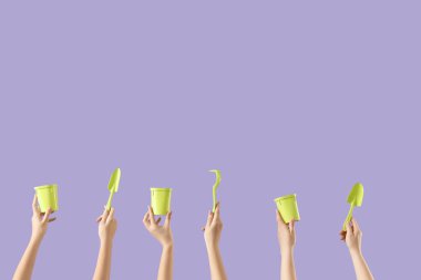 Leylak arka planında bahçe aletleri olan kadın eller