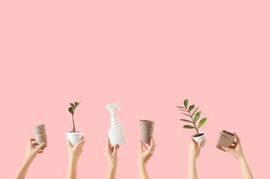 Bahçe aletleri ve pembe arka planda bitkileri olan kadın elleri