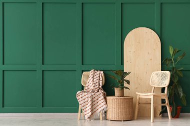 Sepetli sandalye ve yeşil duvarın yanındaki bitkiler.