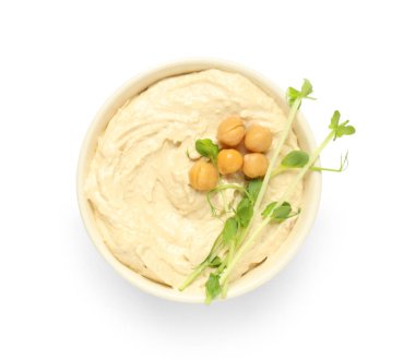 Beyaz zemin üzerinde nohut ve mikro yeşil olan lezzetli humus kasesi.