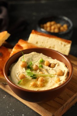 Bir kase lezzetli humus mikro yeşil ve grunge grisi arka planda nohut.