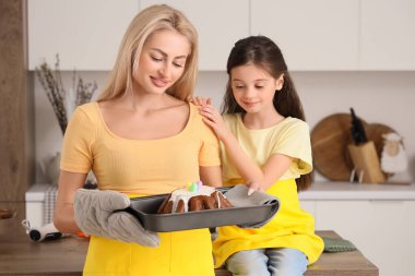 Sevimli kız ve annesi mutfakta Paskalya pastasıyla birlikte yemek tepsisi tutuyorlar.