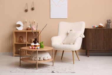 Oturma odasının içinde koltuğu, paskalya pastası ve yumurtaları var.