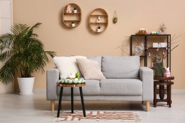 Oturma odasının içinde kanepe, paskalya pastası ve yumurtalar masada.