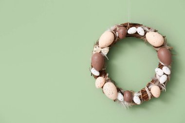 Yeşil duvarda yumurtaları olan Paskalya çelengi