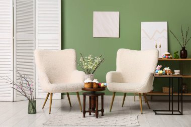 Oturma odasının içinde koltuklar, paskalya pastaları ve yumurtalar var.