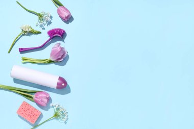 Mavi arka planda bahar çiçekleriyle temizlik malzemeleri