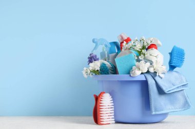 Masada mavi arka planda bahar çiçekleri olan temizlik malzemeleri