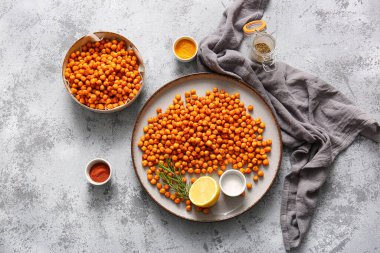 Lezzetli kızarmış bezelye, limon, biberiye ve gri arka planda baharatlar.