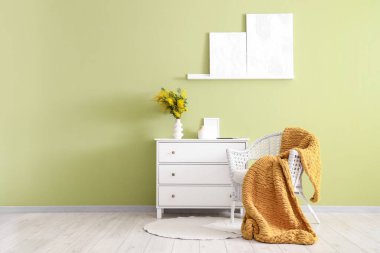 İçinde koltuk, tuvalet ve vazoda mimoza çiçekleri olan bir oda.