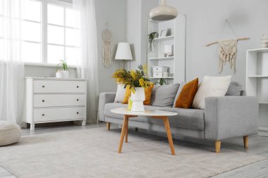 Masadaki vazoda, kanepe ve mimoza çiçekleriyle aydınlık oturma odasının içinde.