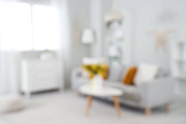 Masasında vazo ve mimoza çiçekleri olan aydınlık oturma odasının bulanık görüntüsü