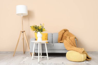 Oturma odasının içinde. Masada vazo ve mimoza çiçekleri var.