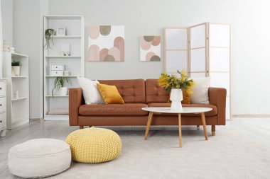 Oturma odasının içinde kanepe, raf ünitesi ve vazoda mimoza çiçekleri var.