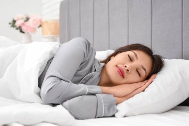 Genç Asyalı kadının yatak odasında yumuşak yastıkta uyuduğu bir sabah.