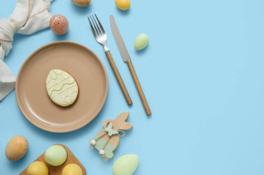 Tatlı kurabiyeli güzel bir masa, Paskalya yumurtaları ve mavi arka planda ahşap bir tavşan.