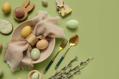 Beautiful table setting with, sweet cookie, Easter eggs and pussy willow branches on green background