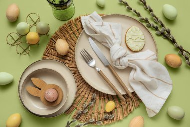 Beautiful table setting with, sweet cookie, Easter eggs and pussy willow branches on green background