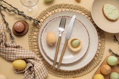 Beautiful table setting with sweet cookie, Easter eggs and pussy willow branches on beige background