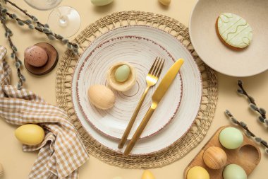 Beautiful table setting with Easter eggs and pussy willow branches on beige background
