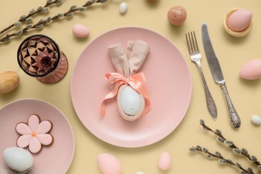 Beautiful table setting with sweet cookie, Easter eggs and pussy willow branches on beige background