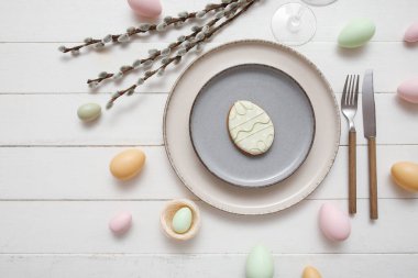 Beautiful table setting with sweet cookie, Easter eggs and pussy willow branches on white wooden background