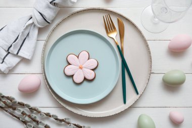 Beautiful table setting with sweet cookie, Easter eggs and pussy willow branches on white wooden background