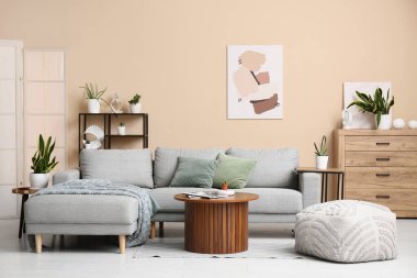 Oturma odasının içinde kanepe, masa ve yeşil bitkiler var.