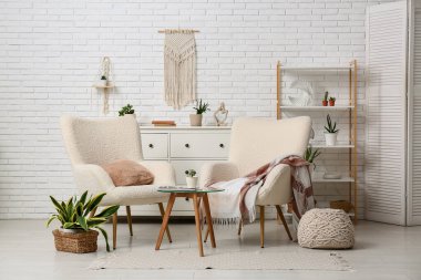 Oturma odasının içinde koltuklar, masa ve yeşil bitkiler