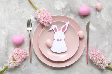 Pembe Paskalya yumurtaları, kağıttan tavşanlar ve gri arka planda güzel çiçekler.