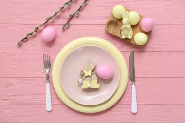Beautiful table setting with Easter eggs, bunnies and pussy willow branches on pink wooden background