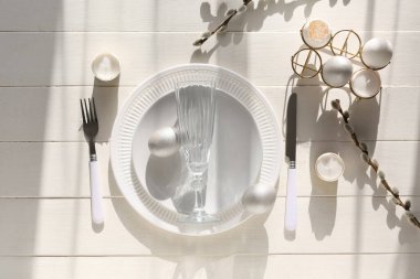Beautiful table setting with Easter eggs, burning candles and pussy willow branches on white tile background