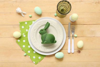 Paskalya yumurtaları ve tahta arka planda oyuncak tavşanla güzel bir masa.