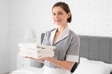 Otel odasında temiz havluları olan genç oda hizmetçisi.