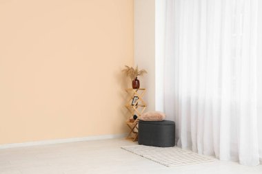 Odadaki ışık perdesinin yanındaki raf üniteli Pouf.