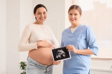 Yatak odasında hamile kadın ve ultrason görüntüsü olan genç doula.