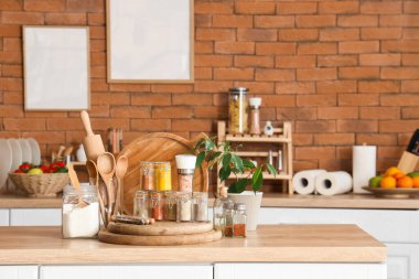 Farklı baharatlı kavanozlar, çatal bıçaklar ve mutfak masasında bitkiler.