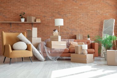 Taşındığı gün oturma odasında karton kutuları olan koltuk ve koltuk.