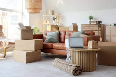 Boş dizüstü bilgisayarlı masa ve taşınma gününde oturma odasında kitaplar.