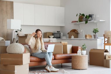 Yeni dairesinden anahtarı olan genç bir kadın ve mutfaktaki kanepede sohbet eden bir dizüstü bilgisayar.