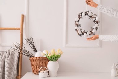 Ofiste ışık duvarı yakınında Paskalya çelengi olan kadın eller.