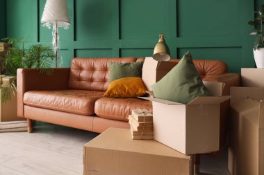 Hareket gününde oturma odasında minderleri ve karton kutuları olan kahverengi kanepe.