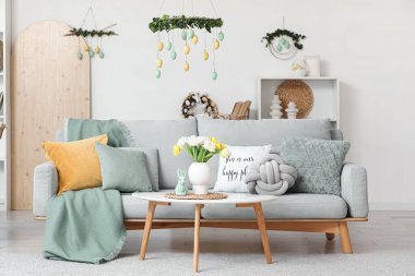 Paskalya için dekore edilmiş oturma odasının içinde kanepe ve masa var.