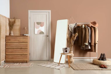 Ayna, çekmece sandığı ve modern koridorun içinde giysi olan raflar.